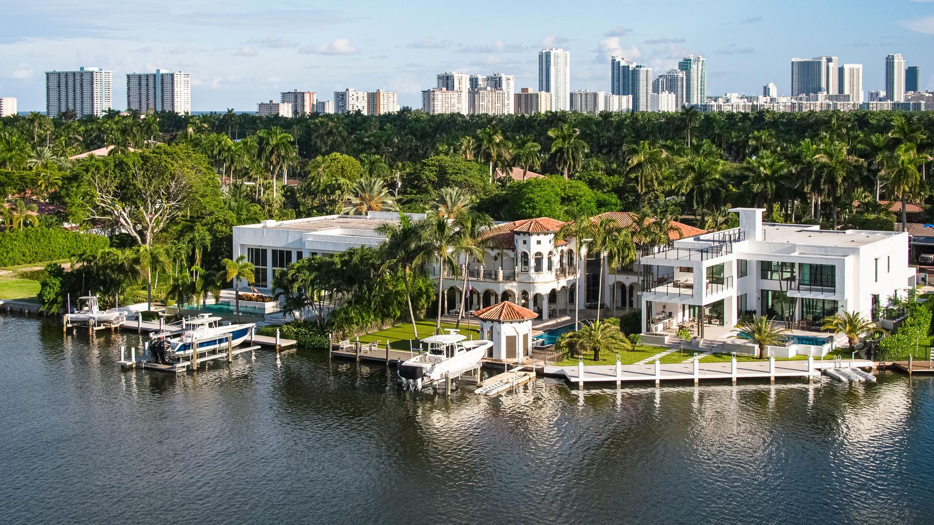 Wealthy coastal neighborhood with villas and mansions along the marina in Hollywood, Florida. Aventura suburbs and Sunny Isles modern buildings aerial view